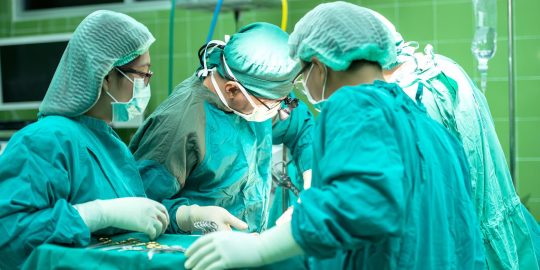 Complex surgery with multiple surgeons working in hospital operating theatre